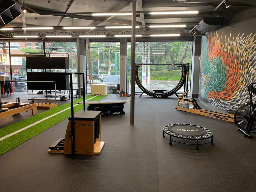 Espaço interno do Studio Mormaii Morumbi, com arte na parede e equipamentos inovadores para um treinamento eficaz.
